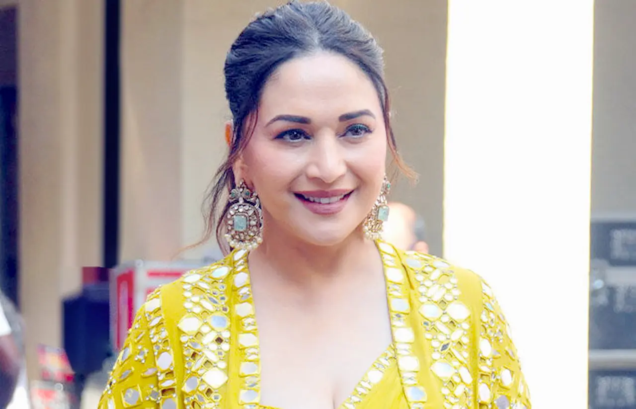 Madhuri Dixit smiling in traditional yellow outfit at an event